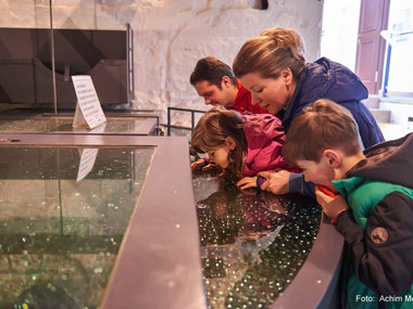 Familie beim Blick in den 152 Meter tiefen Brunnenschacht